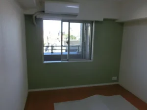 洋室の壁の一面をモスグリーンの壁紙で貼り替えた様子