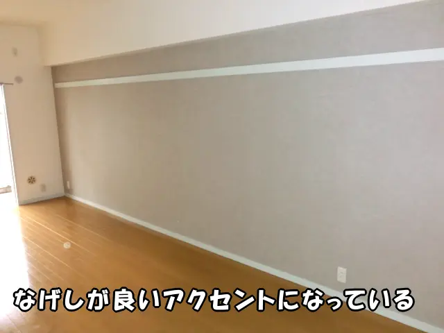 墨田区の公営住宅で、リビングの壁を一面だけグレーの壁紙で貼り替え、なげしが良いアクセントになり、きれいに仕上がった壁の様子。
